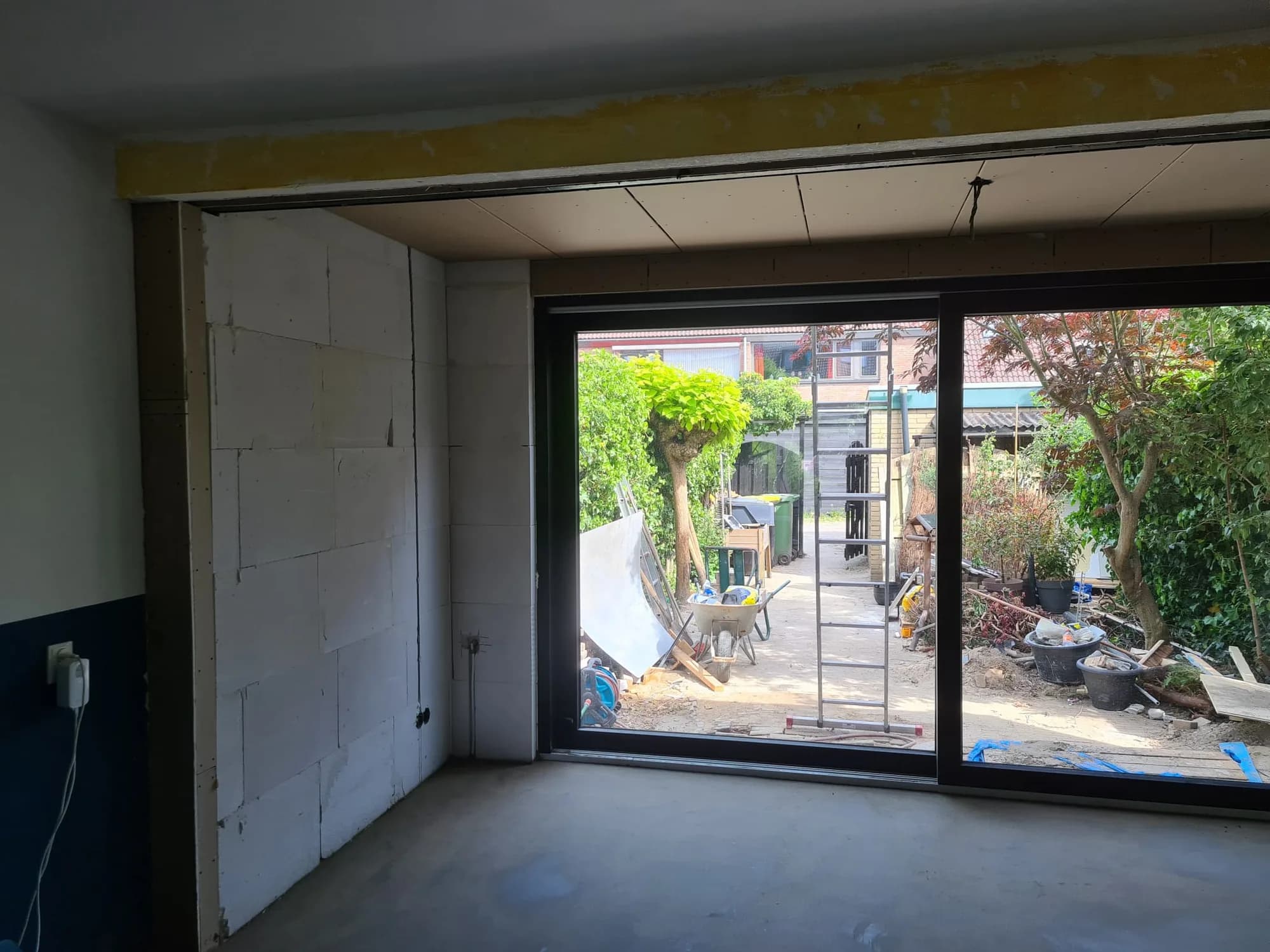 Casco interieur van een aanbouw met kalkzandsteenwanden en nieuwe schuifpui met zicht op de tuin