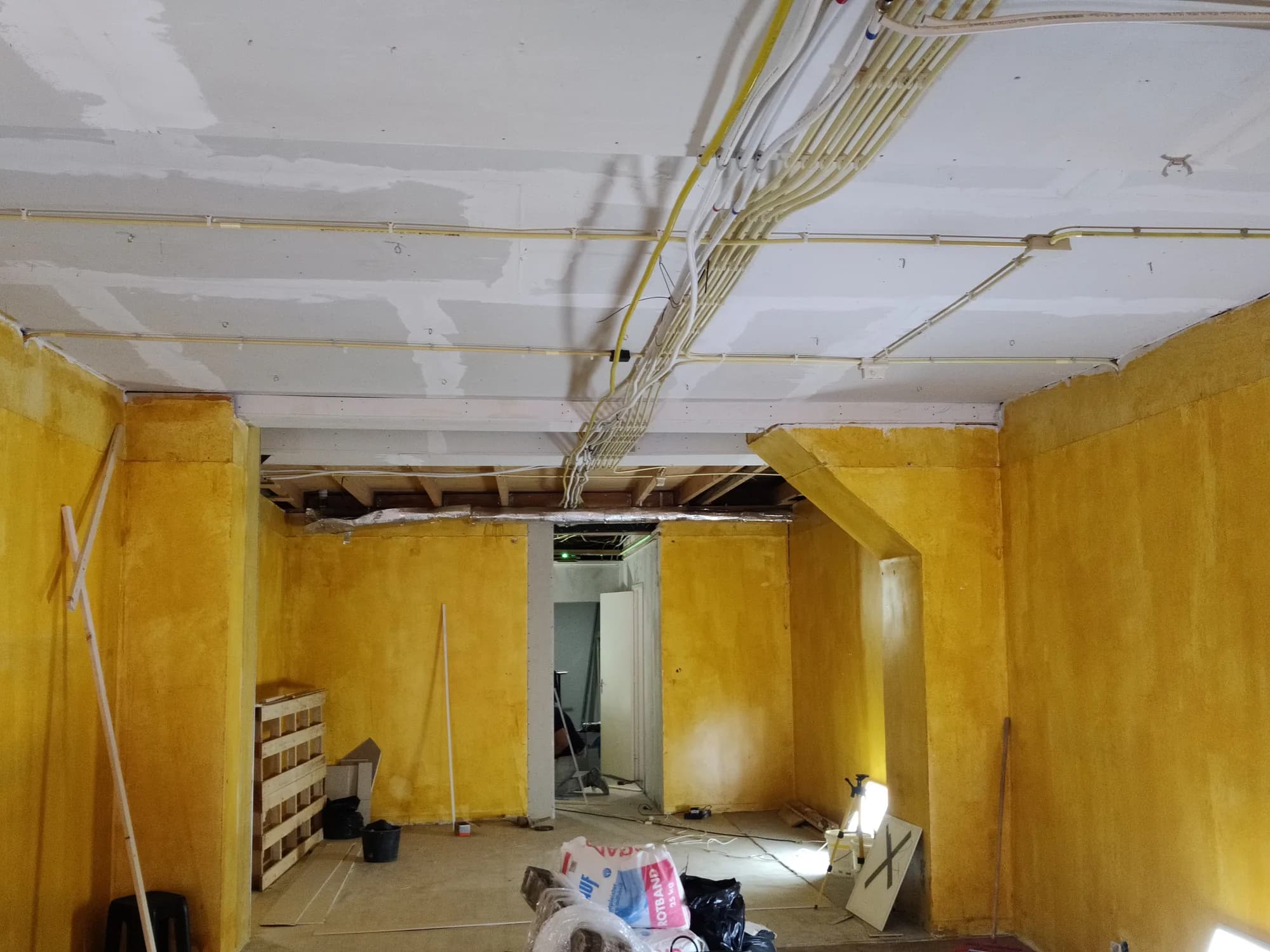 Gestripte woonkamer tijdens renovatie met opengemaakt plafond en zichtbare balklaag