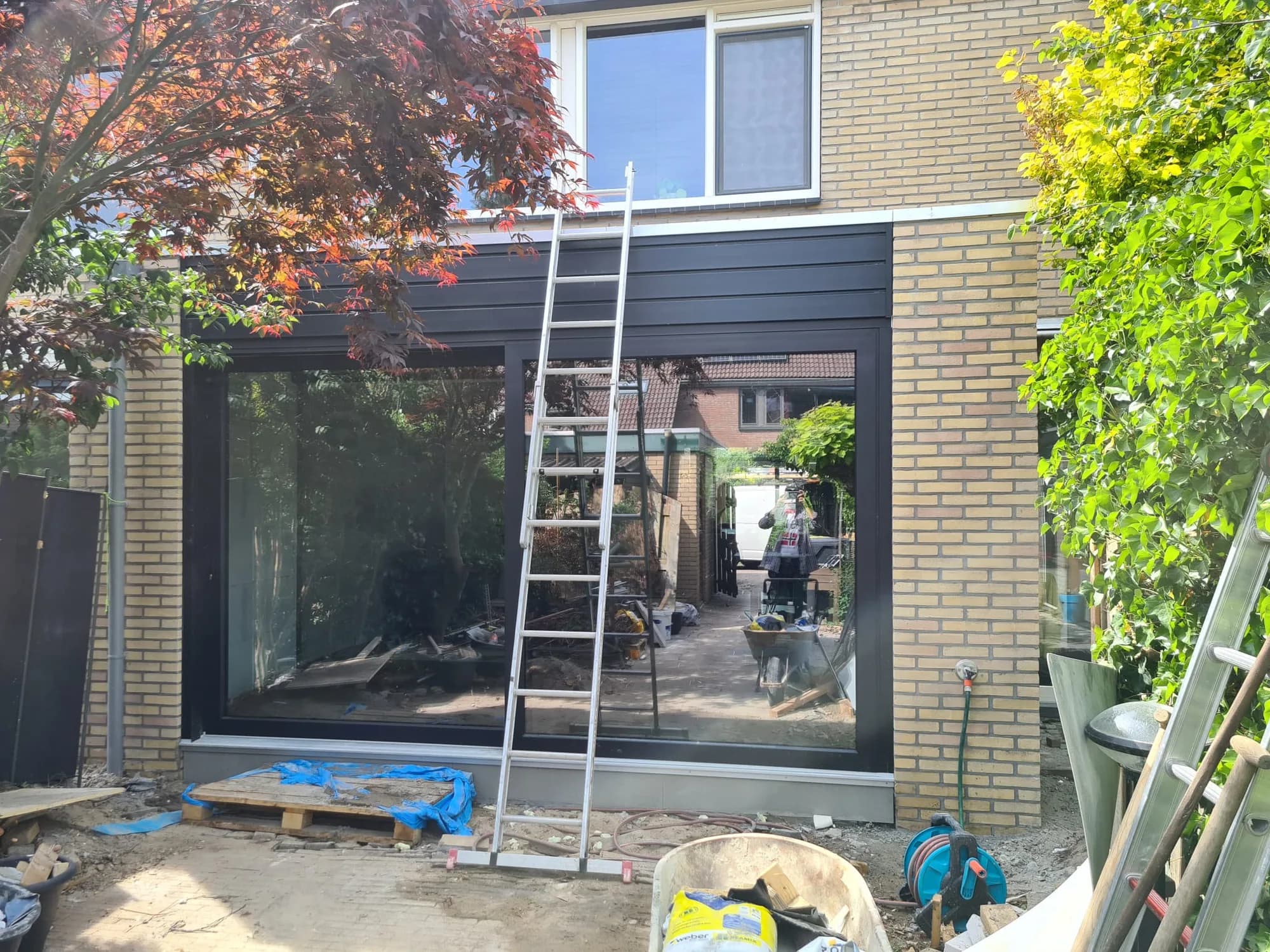 Aanbouw met donkere gevelbekleding en grote glaspui tijdens de afbouwfase