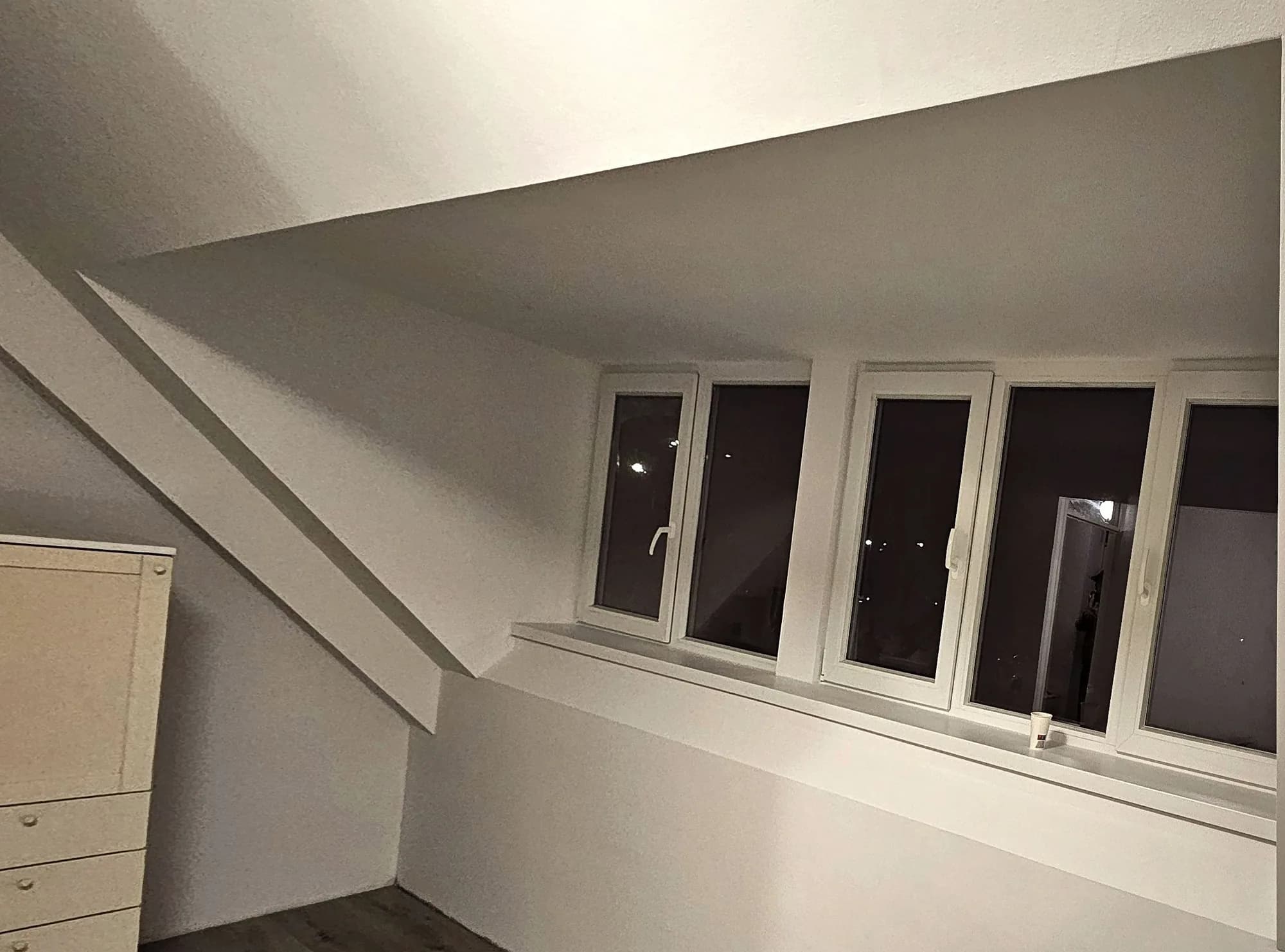 Nieuwe zolderverdieping met witte kozijnen en schuin dak aan de binnenzijde