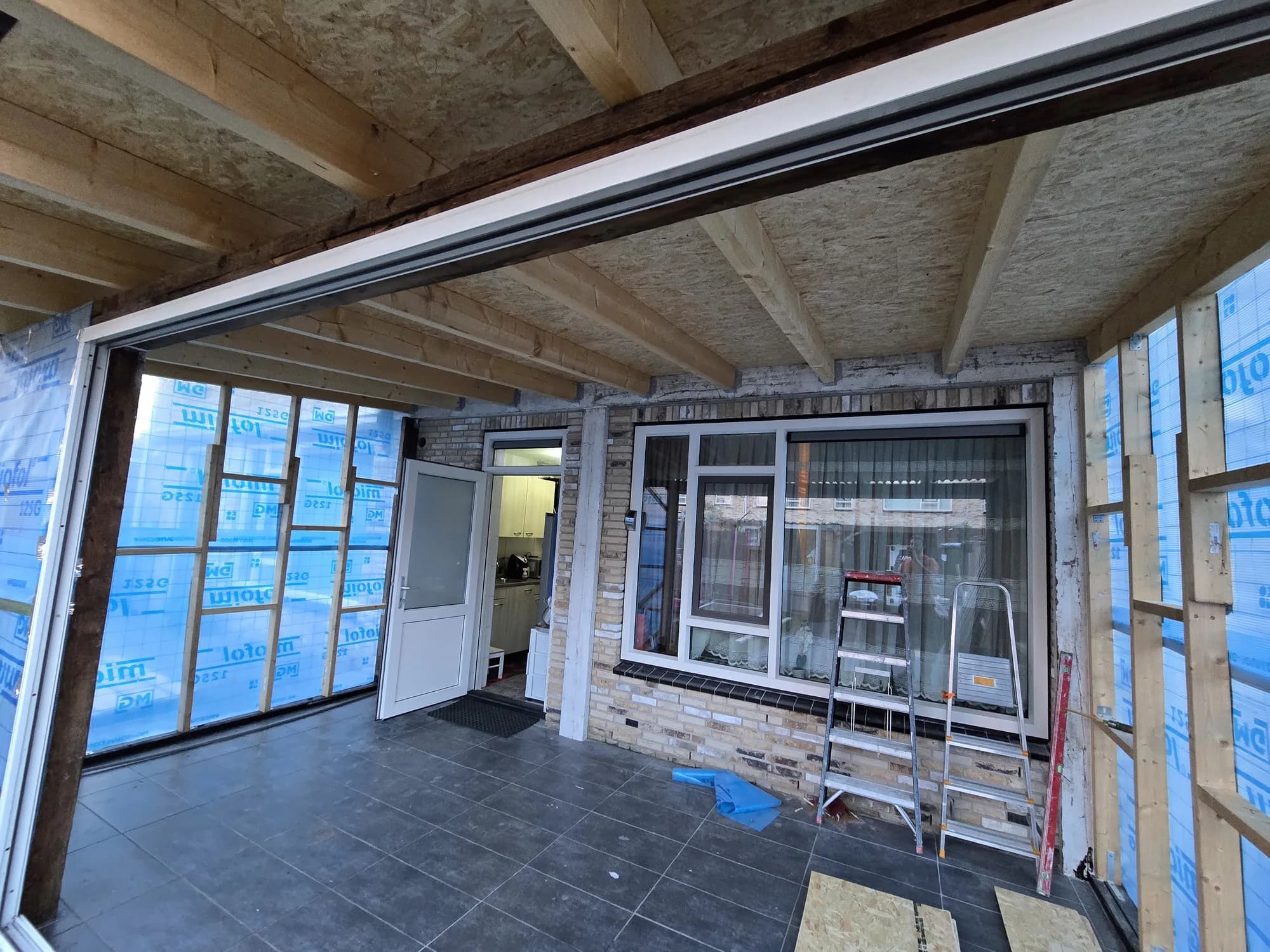 Binnenzijde van een aanbouw in aanbouw met houten balklaag, stijlwerk en dampfolie